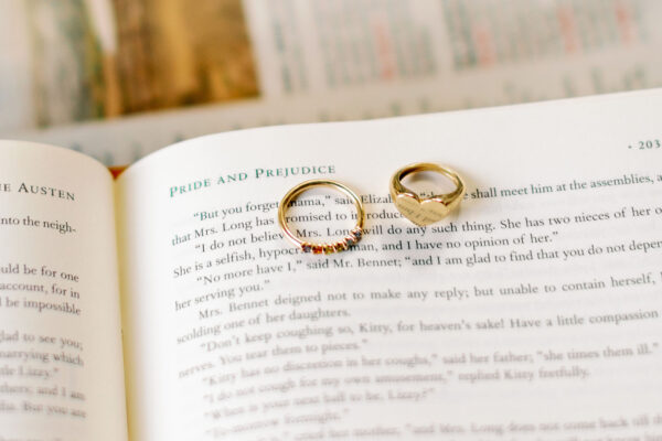 The Muriel Rainbow Ring and The Bunny Hear Signet Ring laying on a book