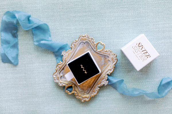 The Claire 14K Gold Arch Ring in a jewelry tray with blue ribbon surrounding it
